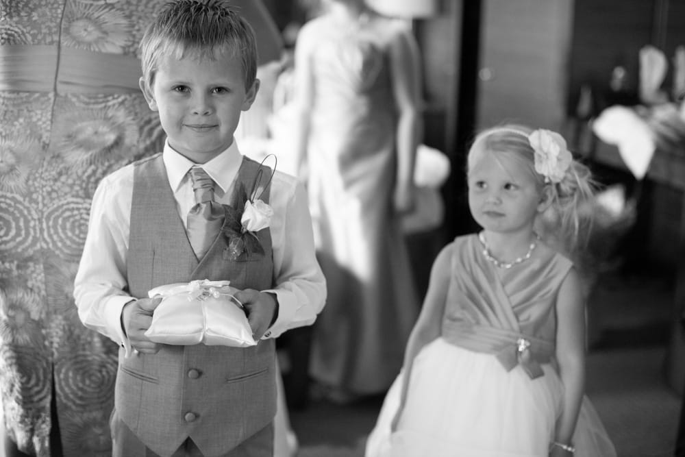 Young pageboy proudly poses with the ring cushion as his sister smiles at him.