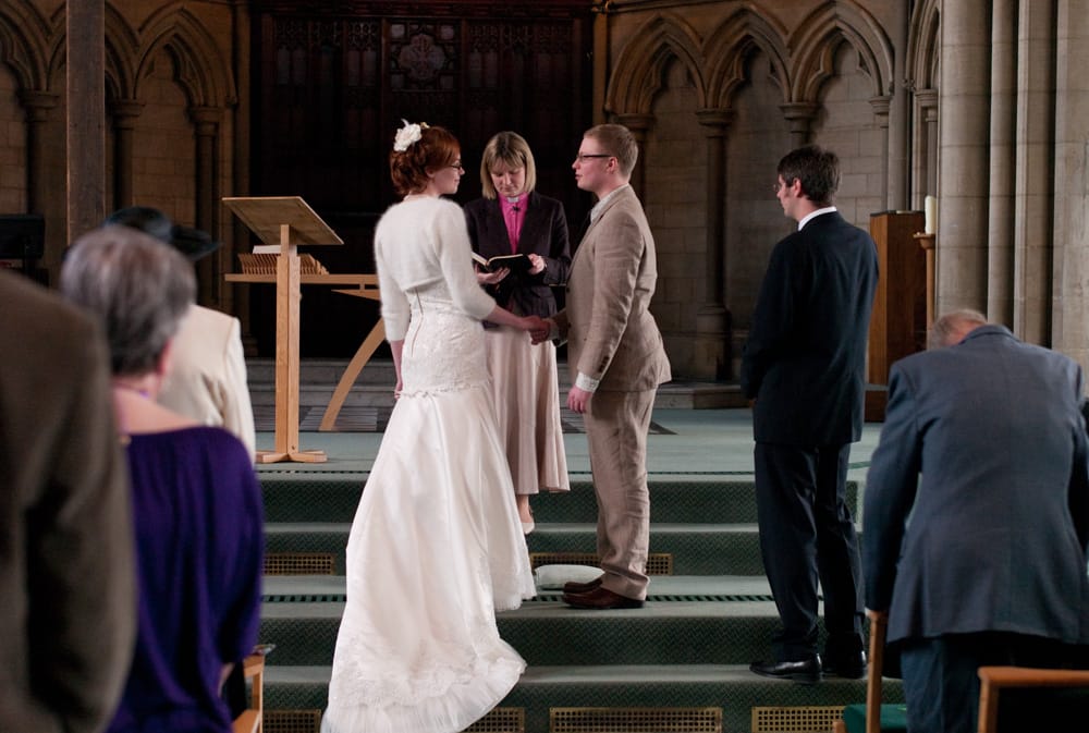 Couple holding hands from behind, stepping carefully at altar of St George’s Leeds.