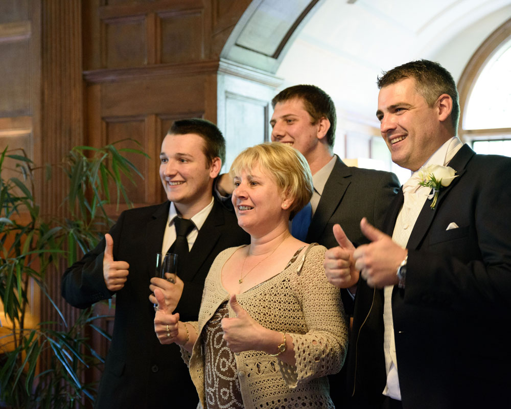 Thumbs up from the groom and family members for someone taking a photo.