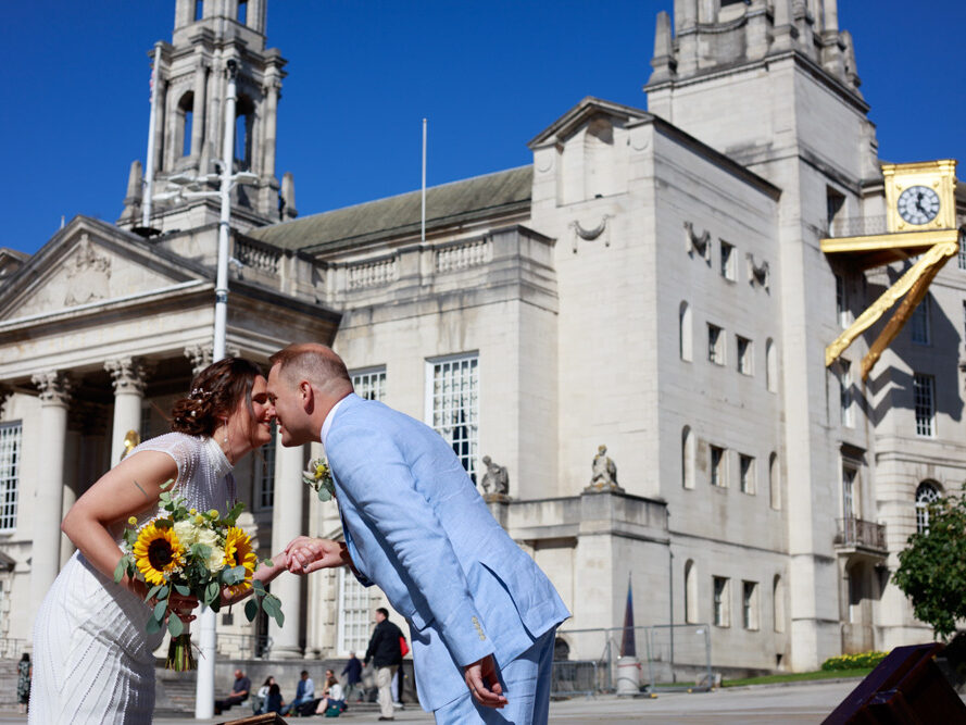 Gemma and Danny kiss on Millennium Square with Leeds Civic Hall behind them.