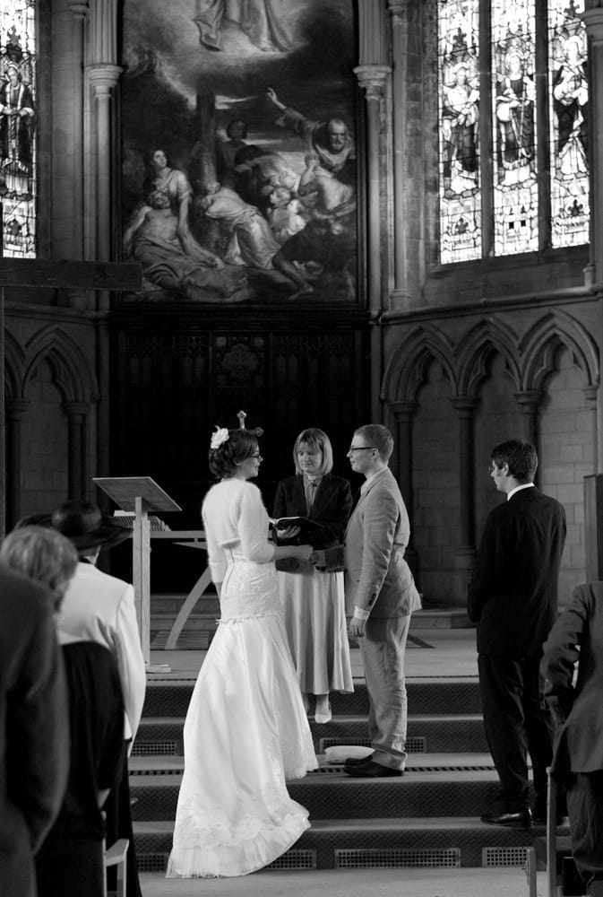 Black and white portrait of couple at altar with ornate church detail above.
