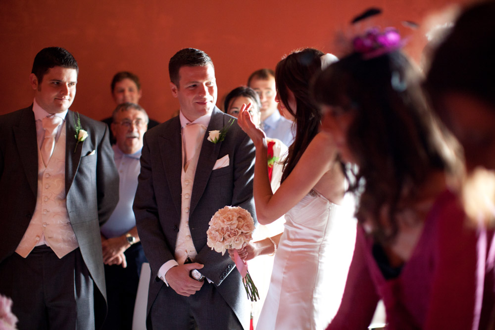Bride wipes a tear and smiles at her groom upon arriving inside the red-walled ceremony space