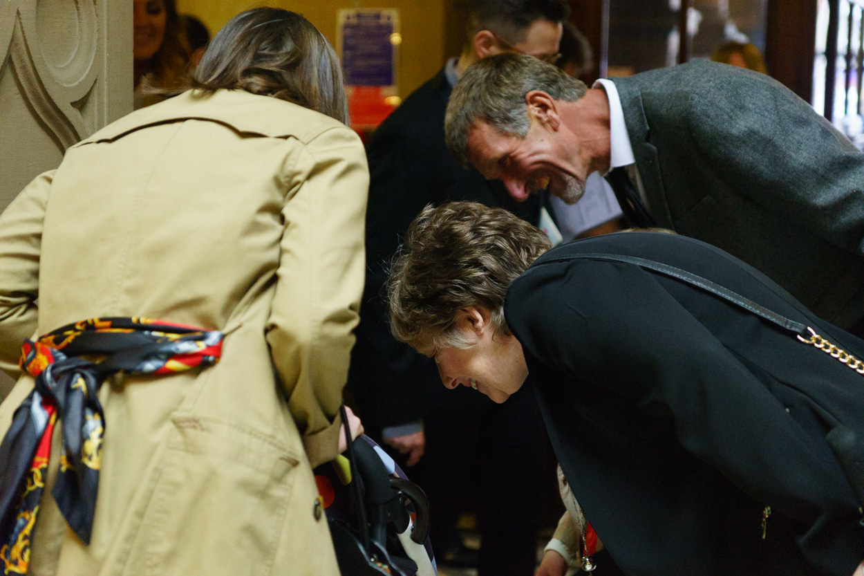 Guests admiring a baby in a pram inside the ceremony space