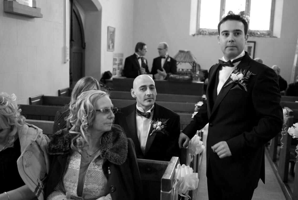 Groom stands with family beside him inside the church.