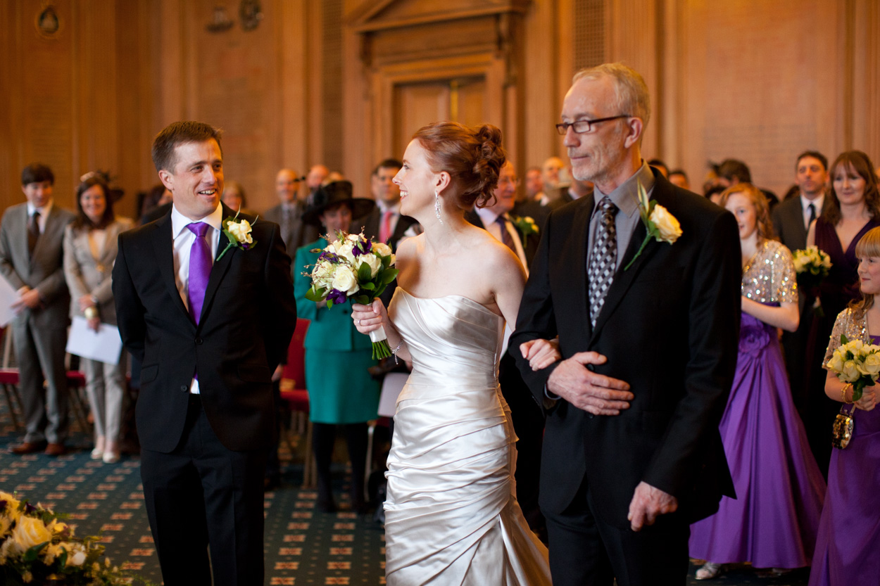 Groom smiling broadly as he sees his bride for the first time.