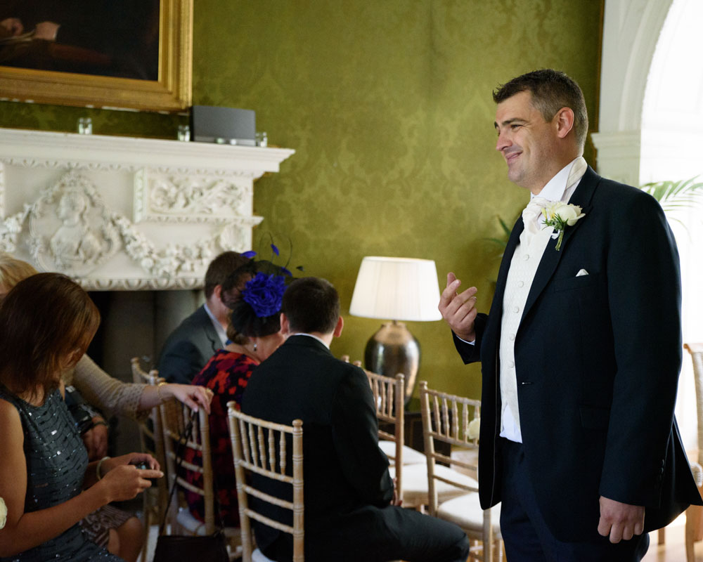 Groom stands smiling at his guests inside Grays Court.