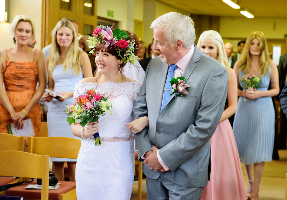 Bride smiles as she approaches the groom during the wedding ceremony in West Yorkshire.