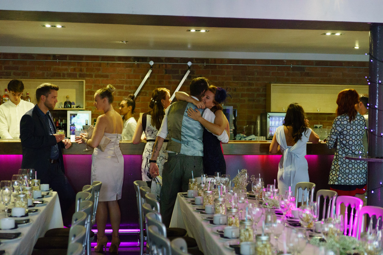 Wedding hugs at the bar with the reception room beyond