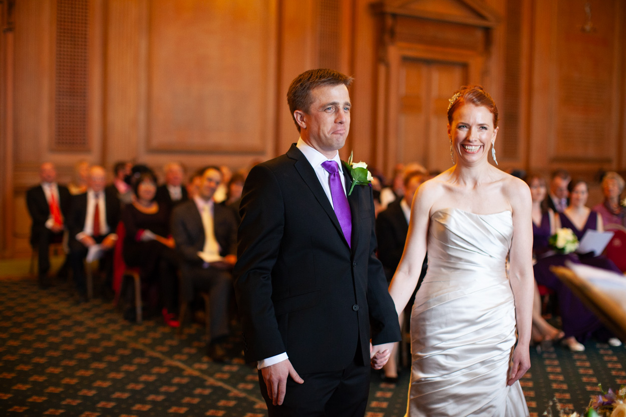 Couple standing hand in hand during the ceremony as guests settle into their seats.