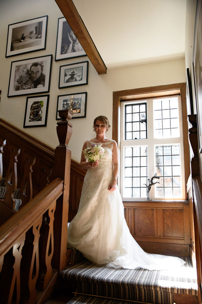 Bride stands mid-way down the staircase at Grays Court near the leaded window.