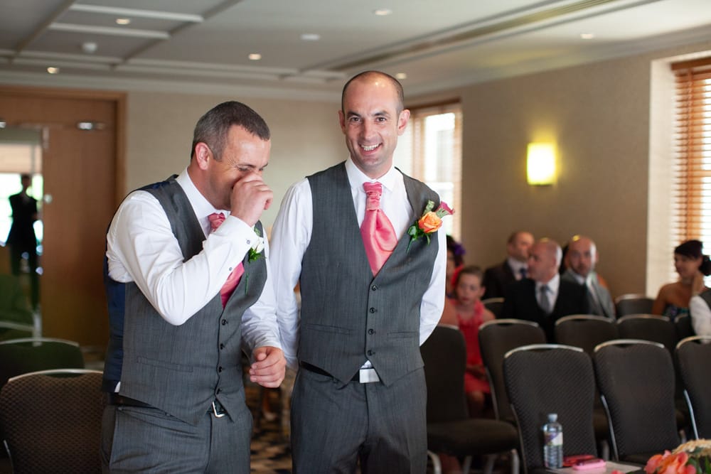 Dave laughs with his best man, who hides his laughter behind his hand.