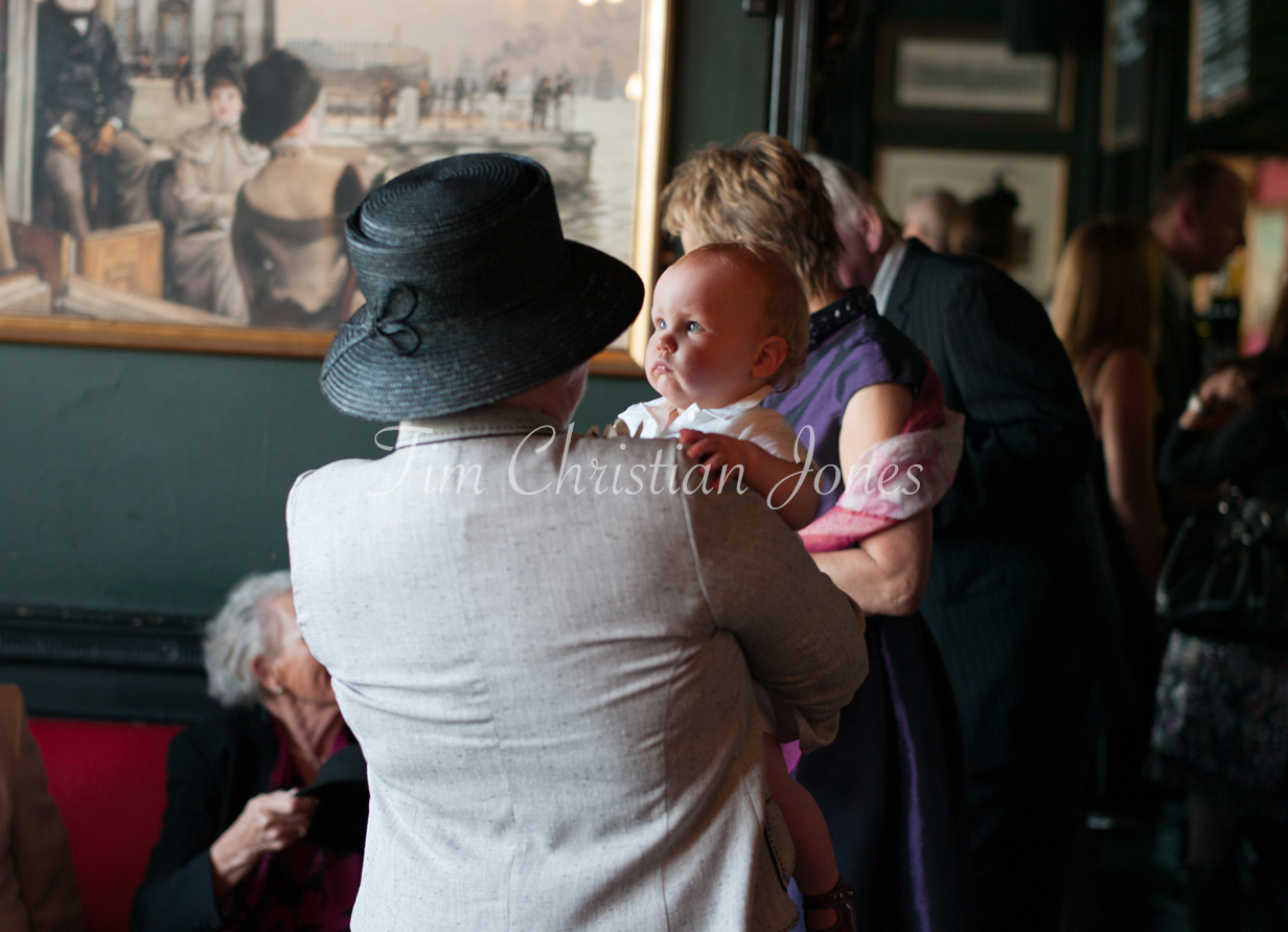 The couple’s young son looks toward his grandmother as guests gather inside the Trafalgar Tavern before the ceremony.