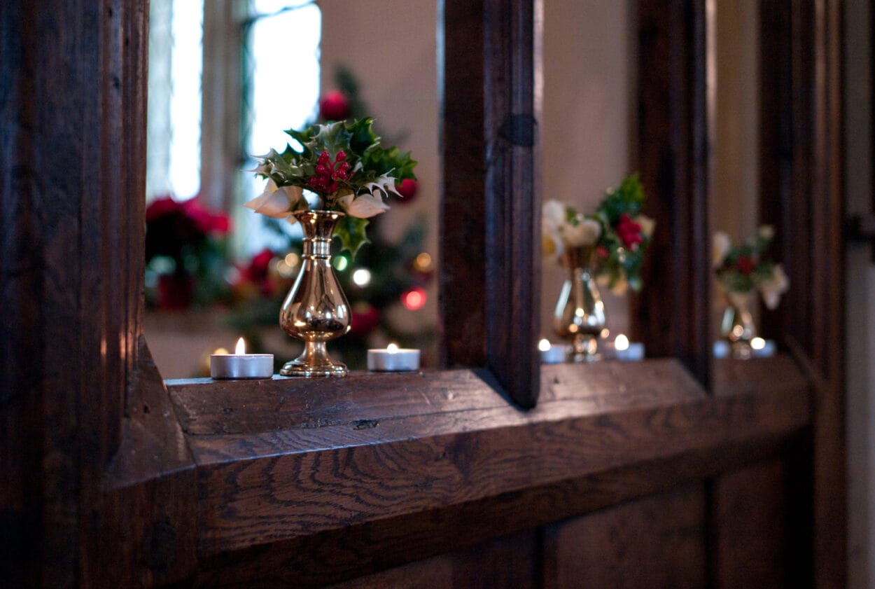 Winter wedding detail: holly and red berries beside candlelight.