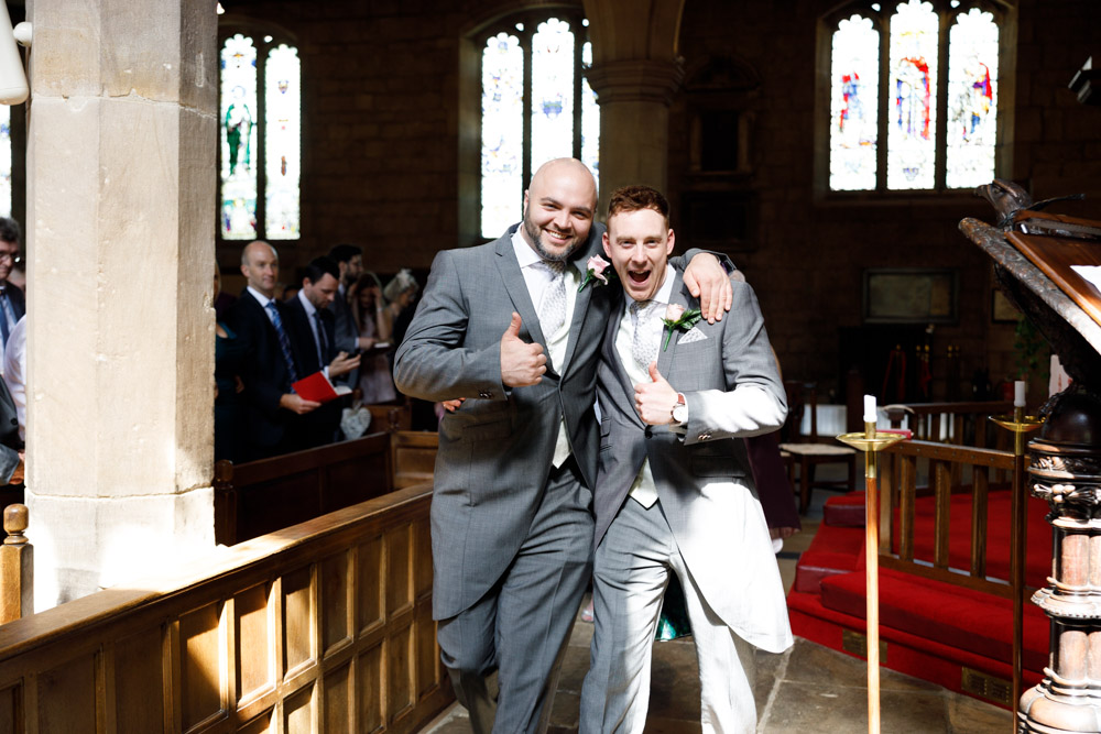 The best men flash thumbs up as they follow the newlyweds into the vestry at St Oswald’s Church.
