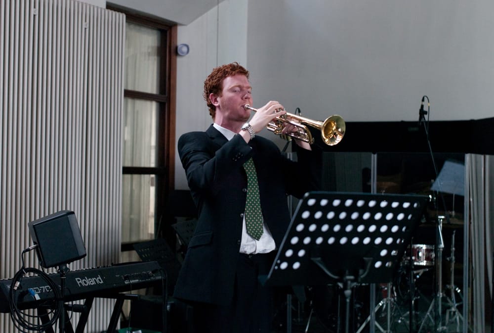 Musician playing trumpet in harmony during church ceremony.