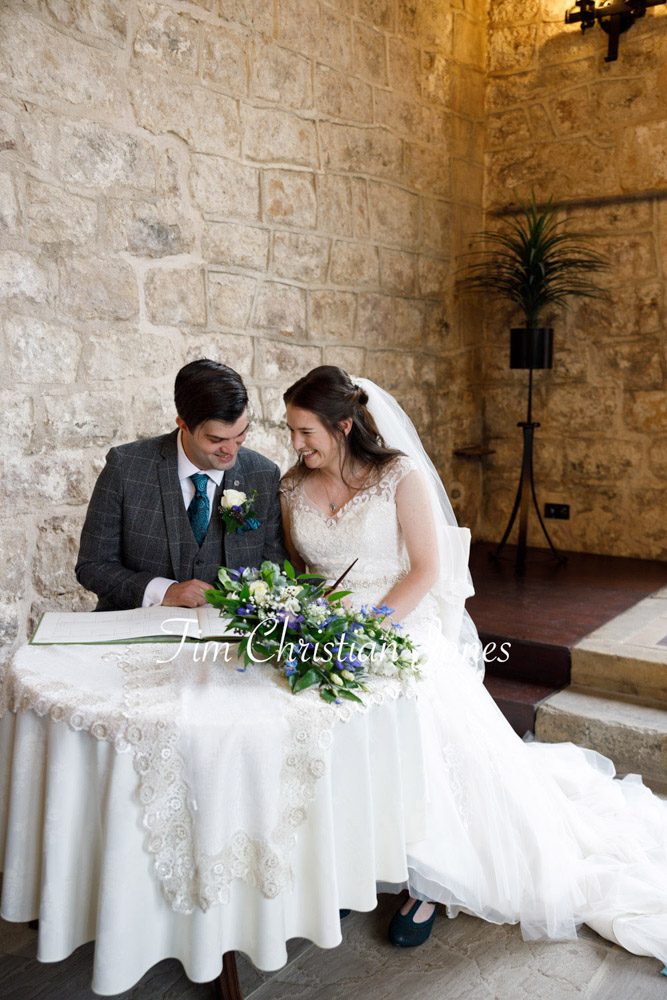 Bride and groom smiling by the wedding register table at The Priests House