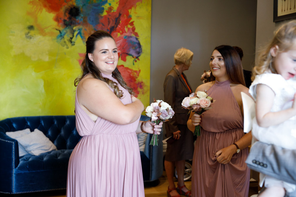Bridesmaids smiling happily in front of a colourful modern art painting