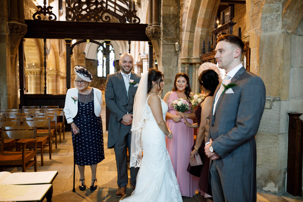 The wedding party gathered in the vestry, chatting and waiting as the minister completes the register.