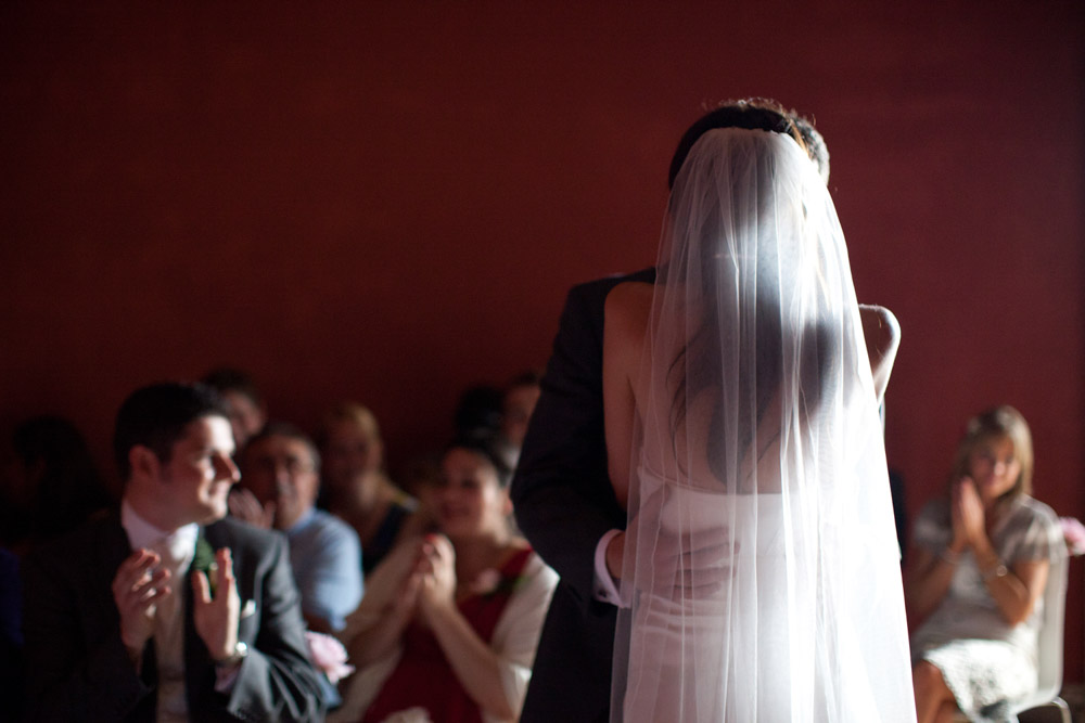 Bride and groom share their first kiss in colour as guests applaud during the ceremony