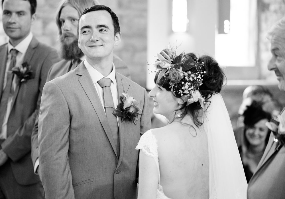 Bride and groom close up during the ceremony, smiling softly and looking forward.