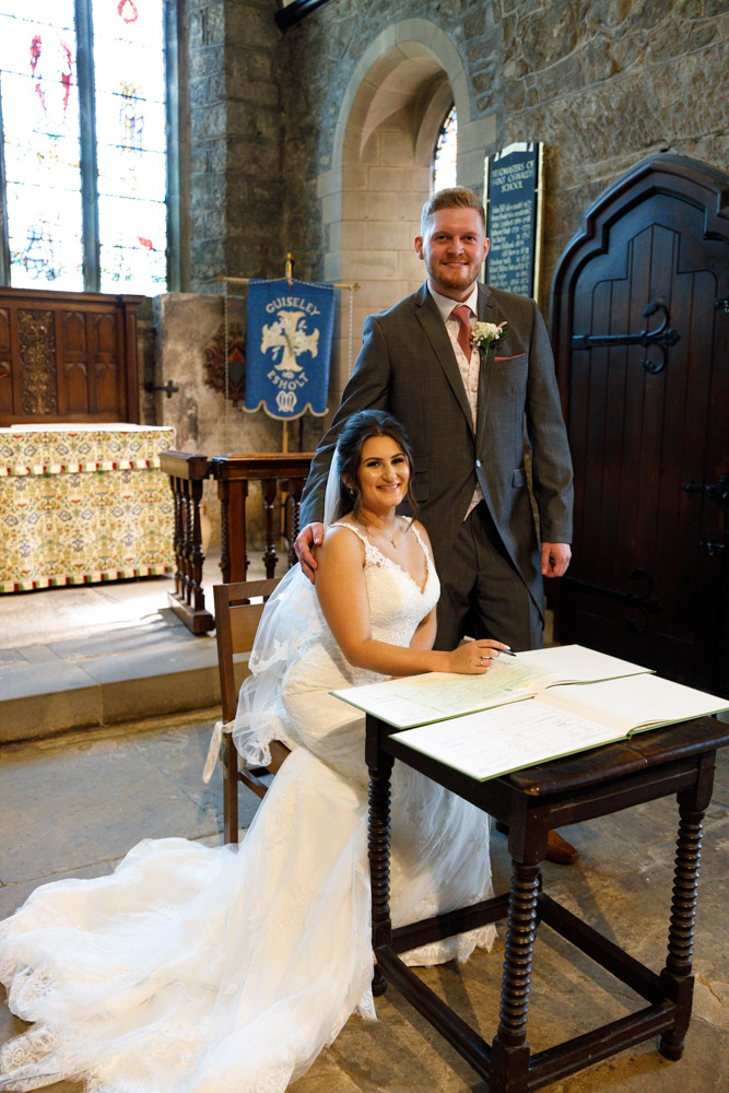 Kyra and Matt at the register table, wedding dress fanned out as they pose with quiet pride.