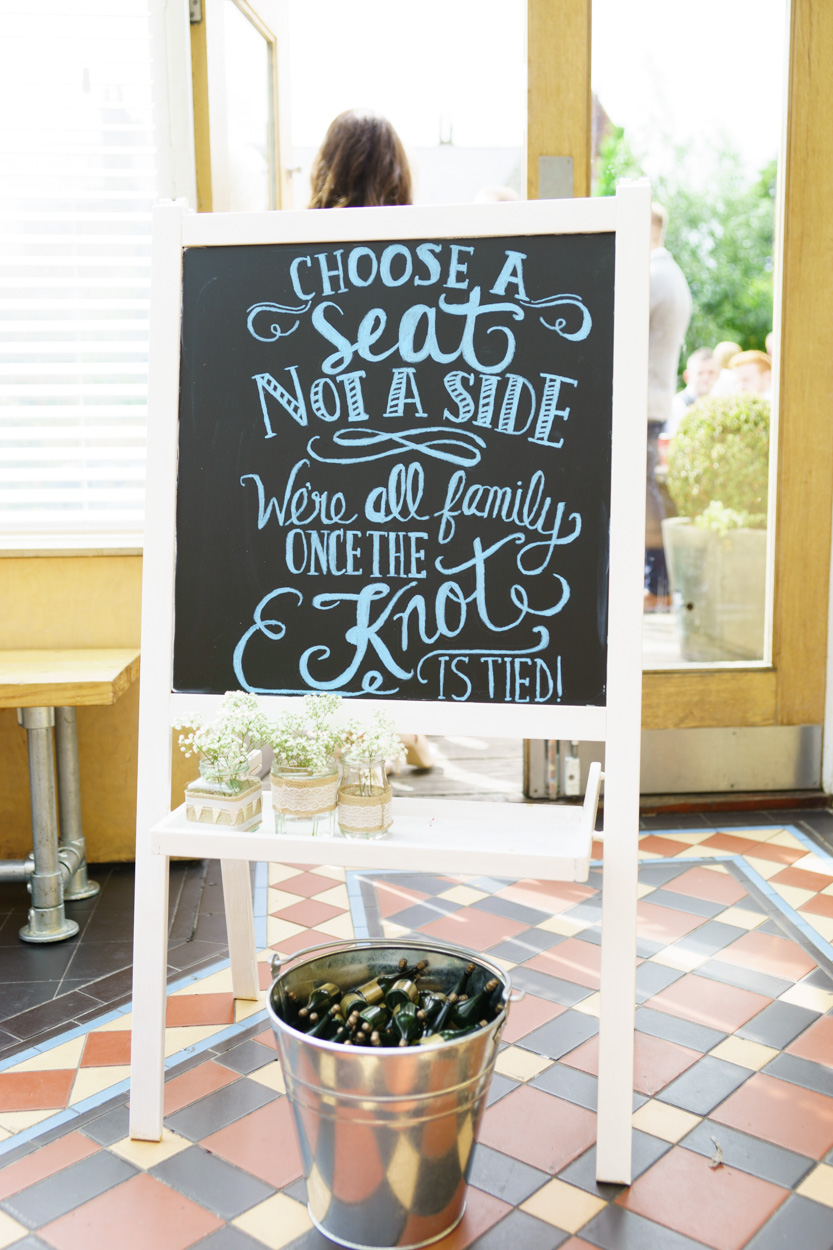 “Choose a seat, not a side” wedding sign