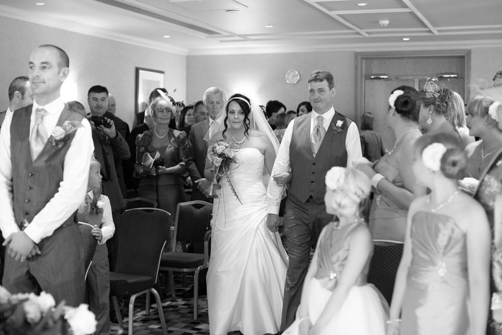 Black and white — Gemma glances towards her daughters as she walks the aisle with her father.