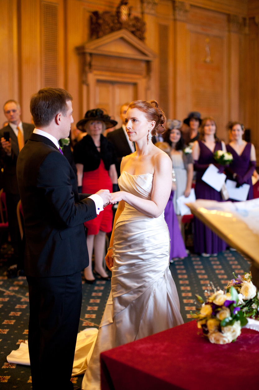 Groom placing the wedding ring on the bride’s finger as vows are spoken.