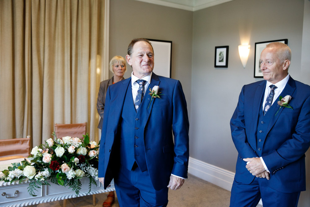 Groom smiles warmly as Tracy approaches from down the aisle
