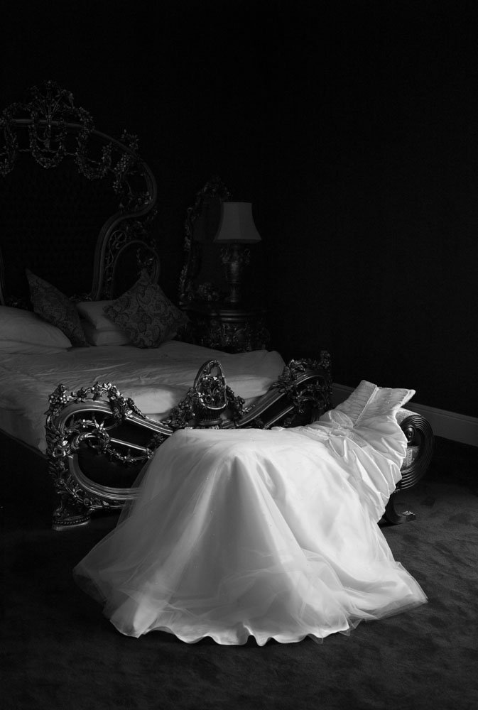 Portrait-style black and white of the wedding dress hanging poised and elegant.