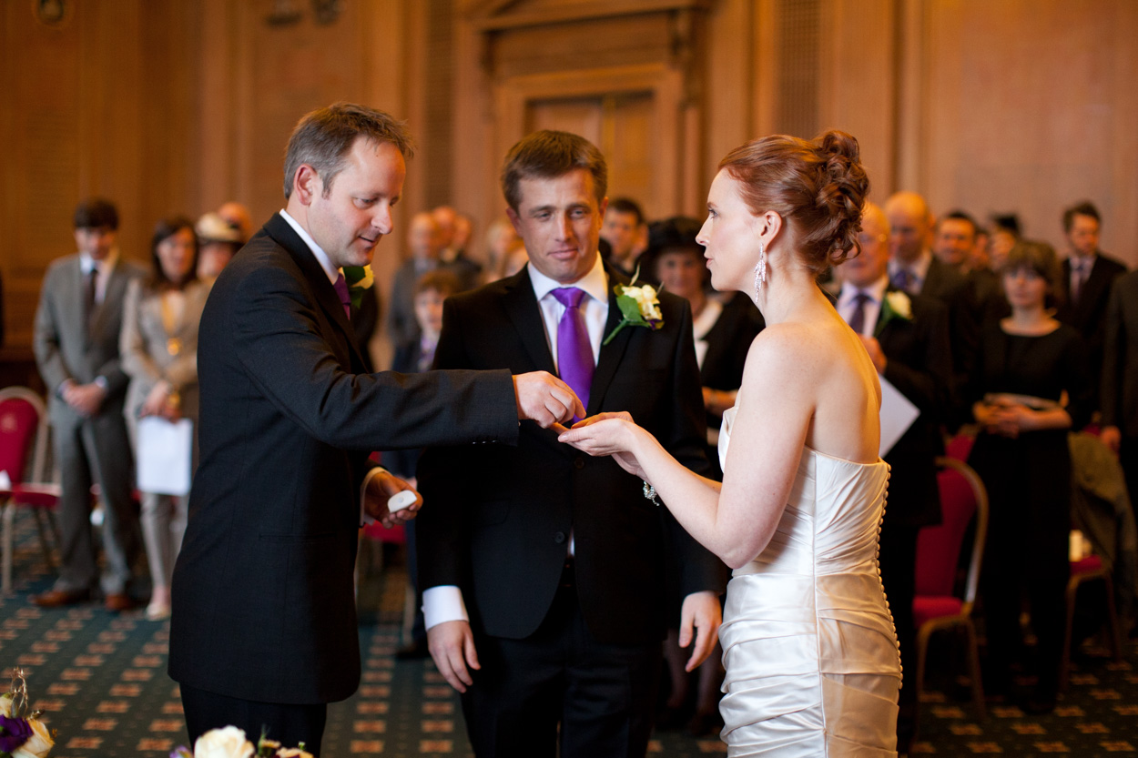 Best man handing the groom’s ring to the bride during the ceremony.