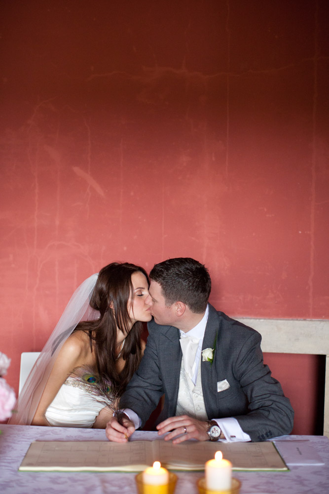 Bride and groom share a kiss at the signing table during the ceremony