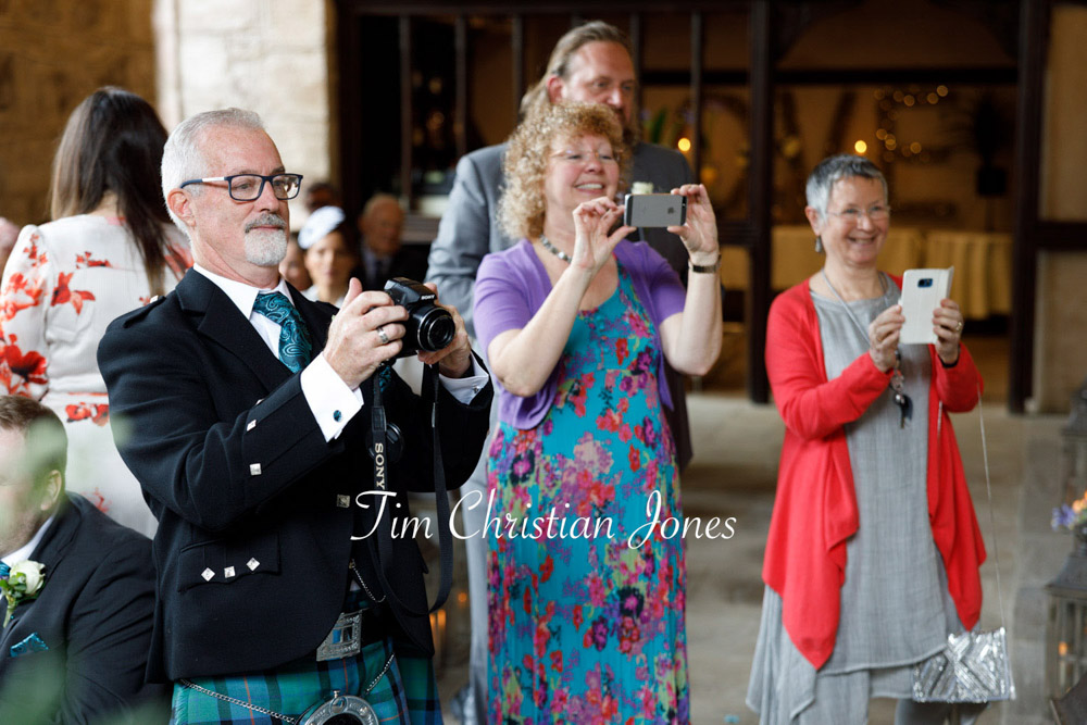 Guests capturing a sweet wedding moment with the couple and pageboy.