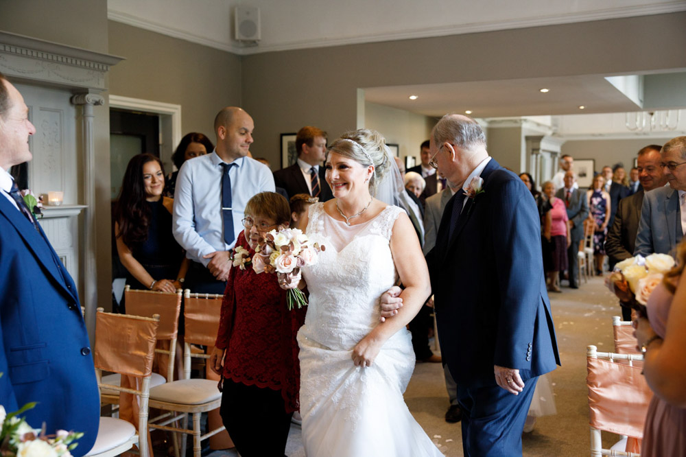 Tracy smiles widely as she reaches her groom at the altar