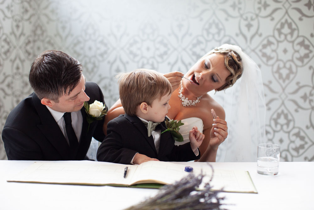 At the register table, Sam applies lip gloss as their son joins them.