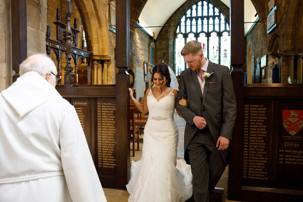 Kyra and Matt exit the vestry — she steps carefully down, watched by the minister.