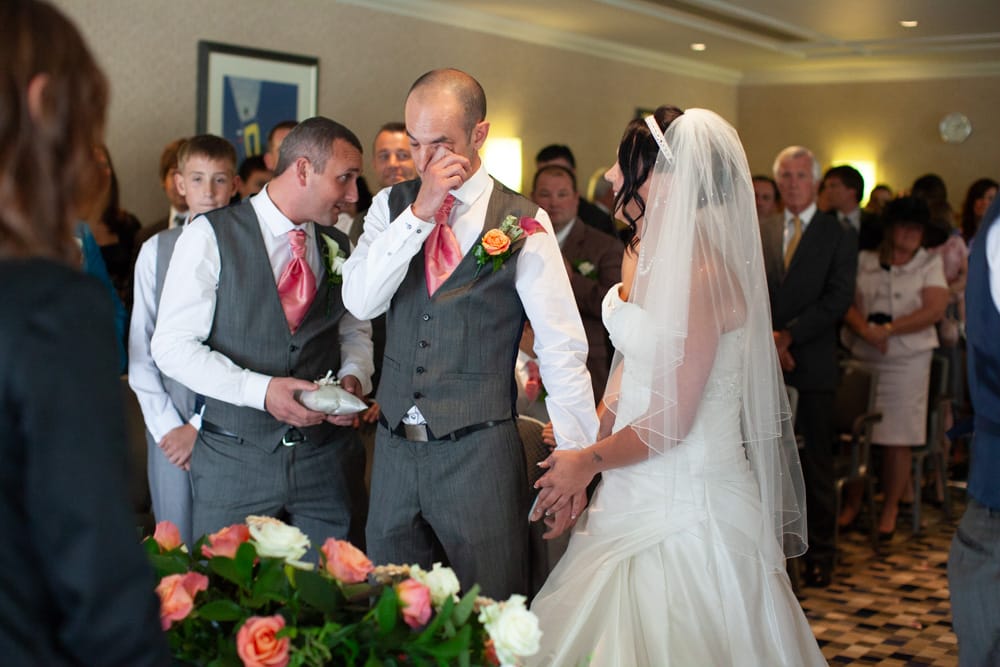 Best man holds the rings while Dave wipes his eyes, Gemma smiling and holding his hand.
