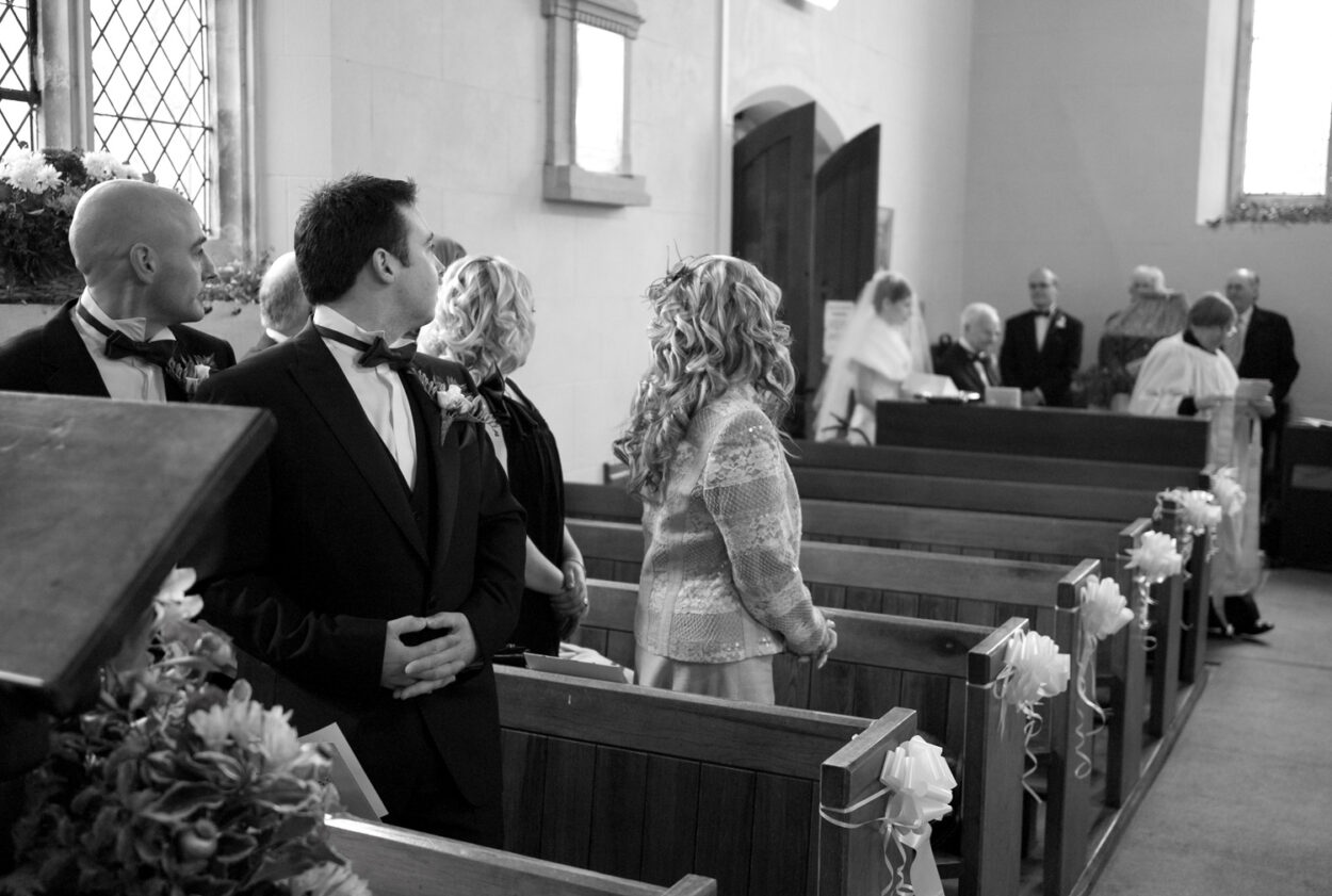 The groom looks back as Emelie and grandad enter the church.