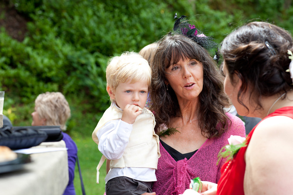 Wedding guests mingle outside in the sunshine after the ceremony