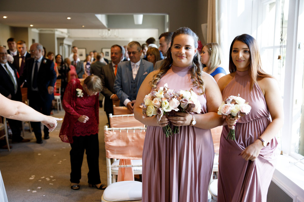 Bridesmaids looking on lovingly while guests remain standing