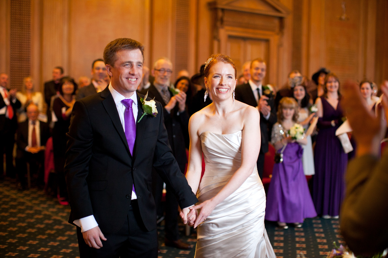 Bride and groom smiling widely after their first kiss.