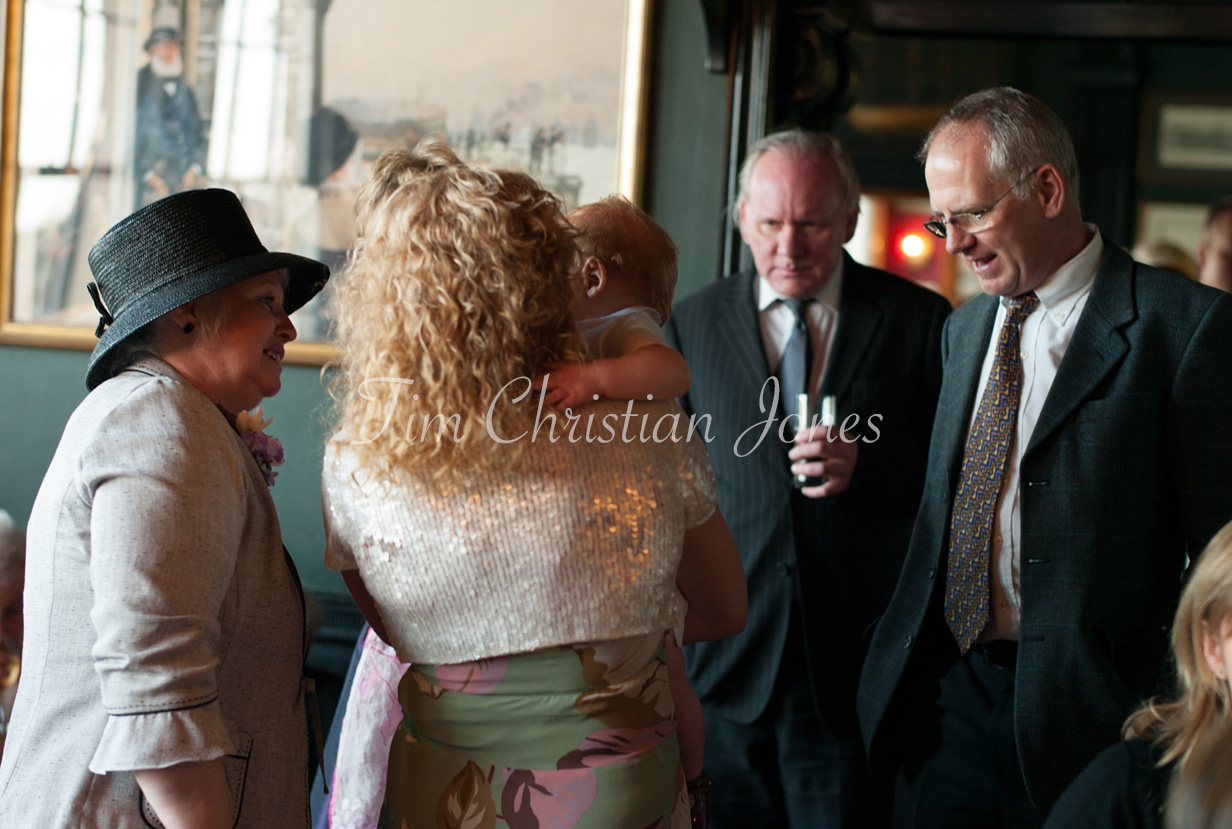 Guests mingling in the warm interior of the Trafalgar Tavern, filled with soft light and laughter.