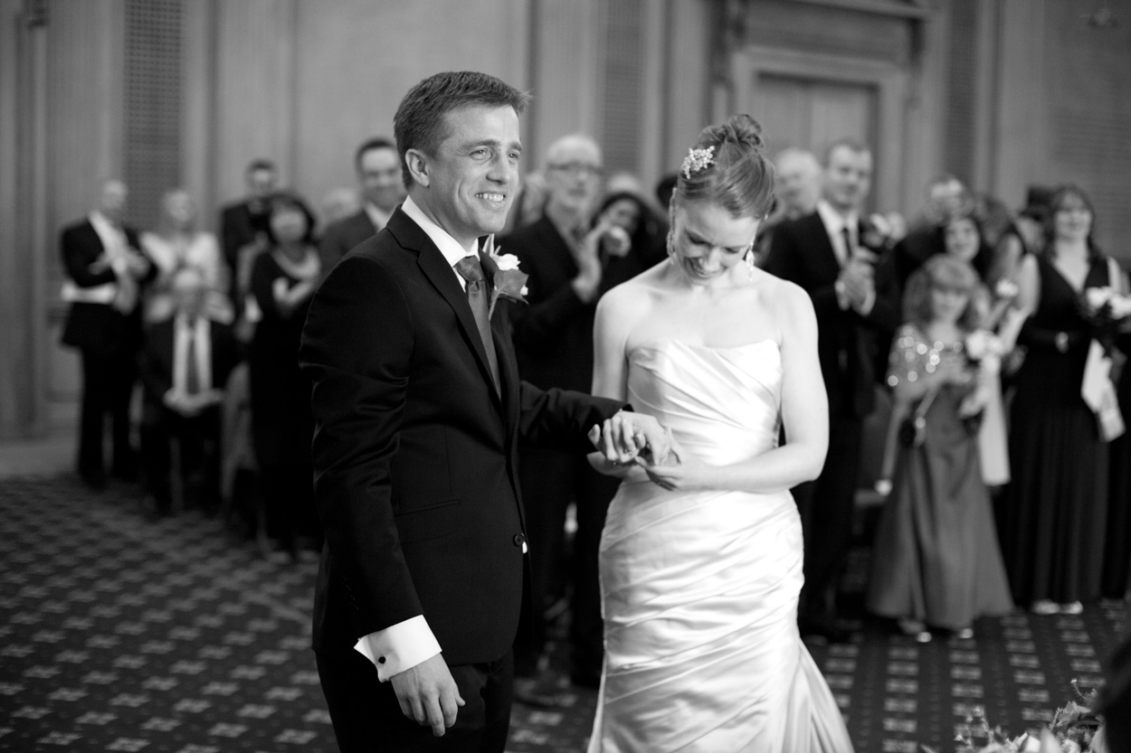 Black and white image of the bride looking down at their clasped hands and rings.