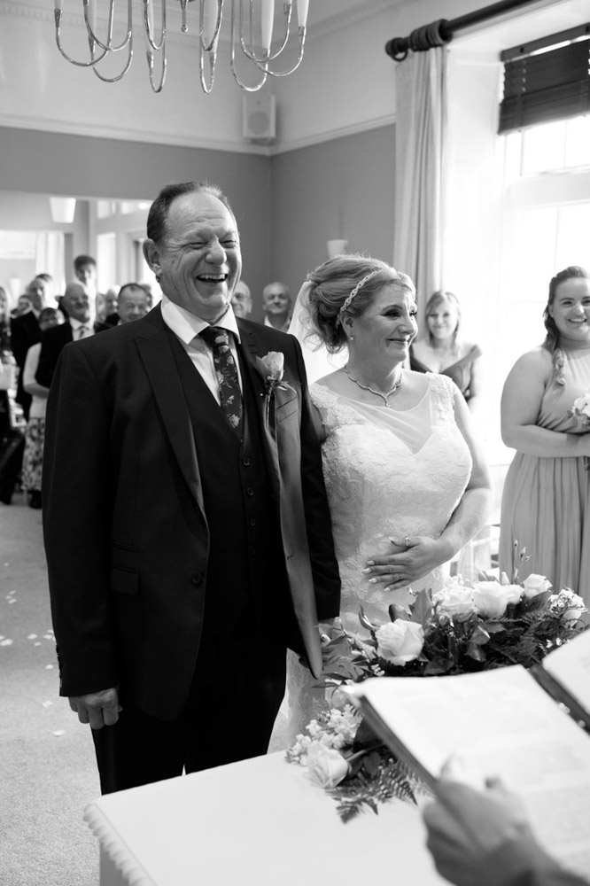 Couple smile at the registrar, standing side by side in black and white