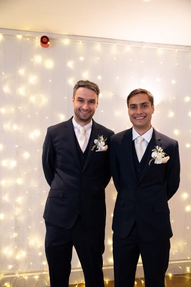The groom and best man posed beneath fairy lights inside the Chilli Barn, Otley.