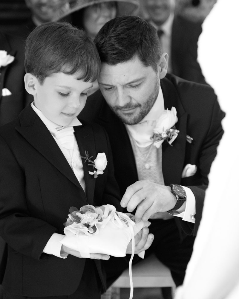 Best man helps the ring bearer prepare during the wedding ceremony.