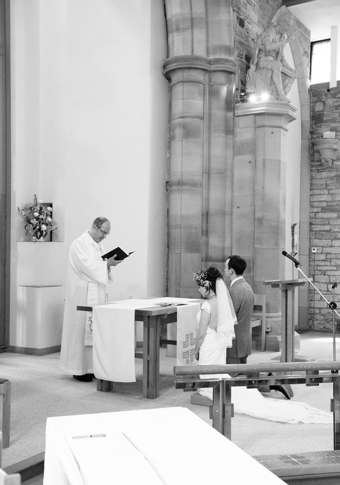 Black and white portrait-style shot of couple kneeling during blessing at St Paul’s Church.