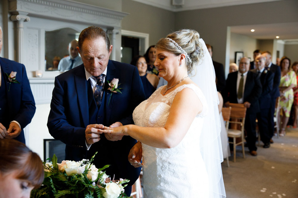 Groom places the wedding ring on Tracy’s finger during the ceremony
