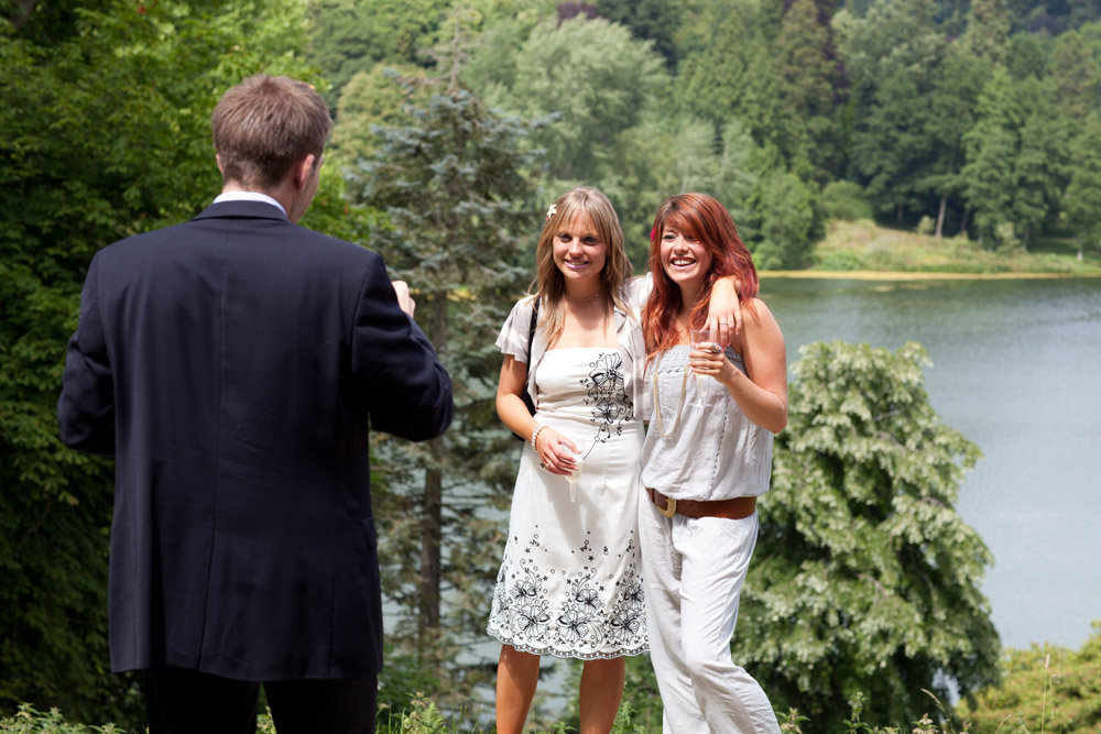 Guests taking photos by the lakeside at a West Yorkshire wedding garden venue