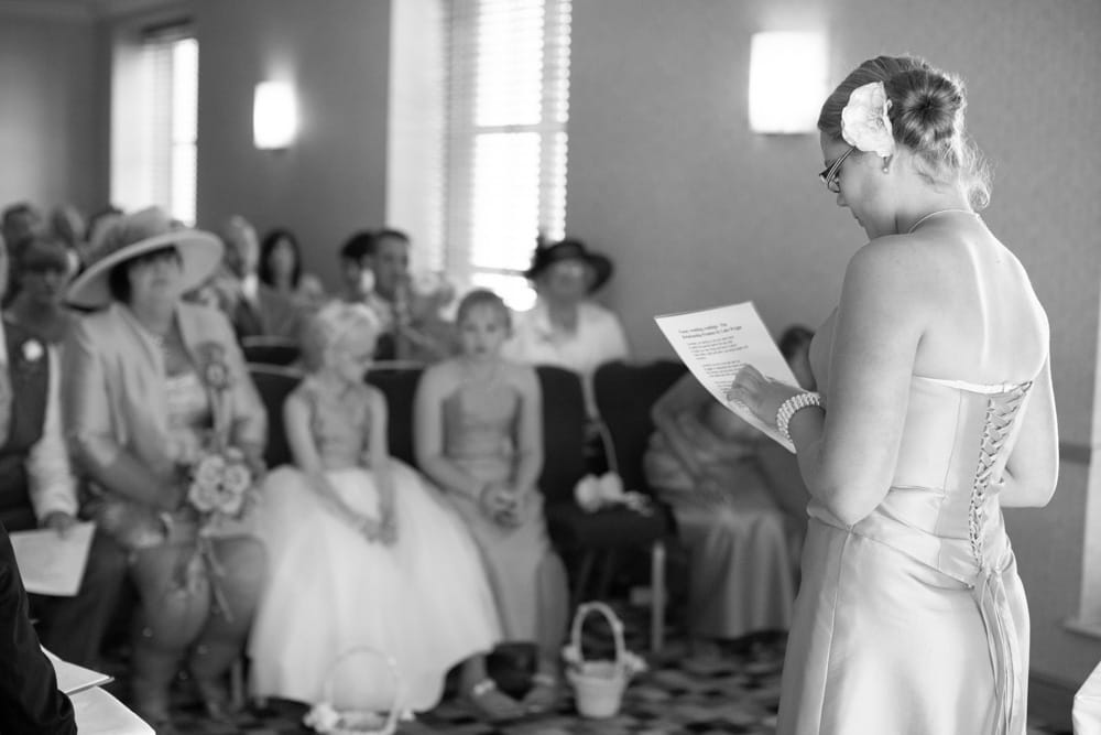 Teenage bridesmaid gives the first reading in black and white during the ceremony.